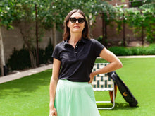 Load image into Gallery viewer, Model wearing Criquet - Women&#39;s Short Sleeve Performance Polo in Black.
